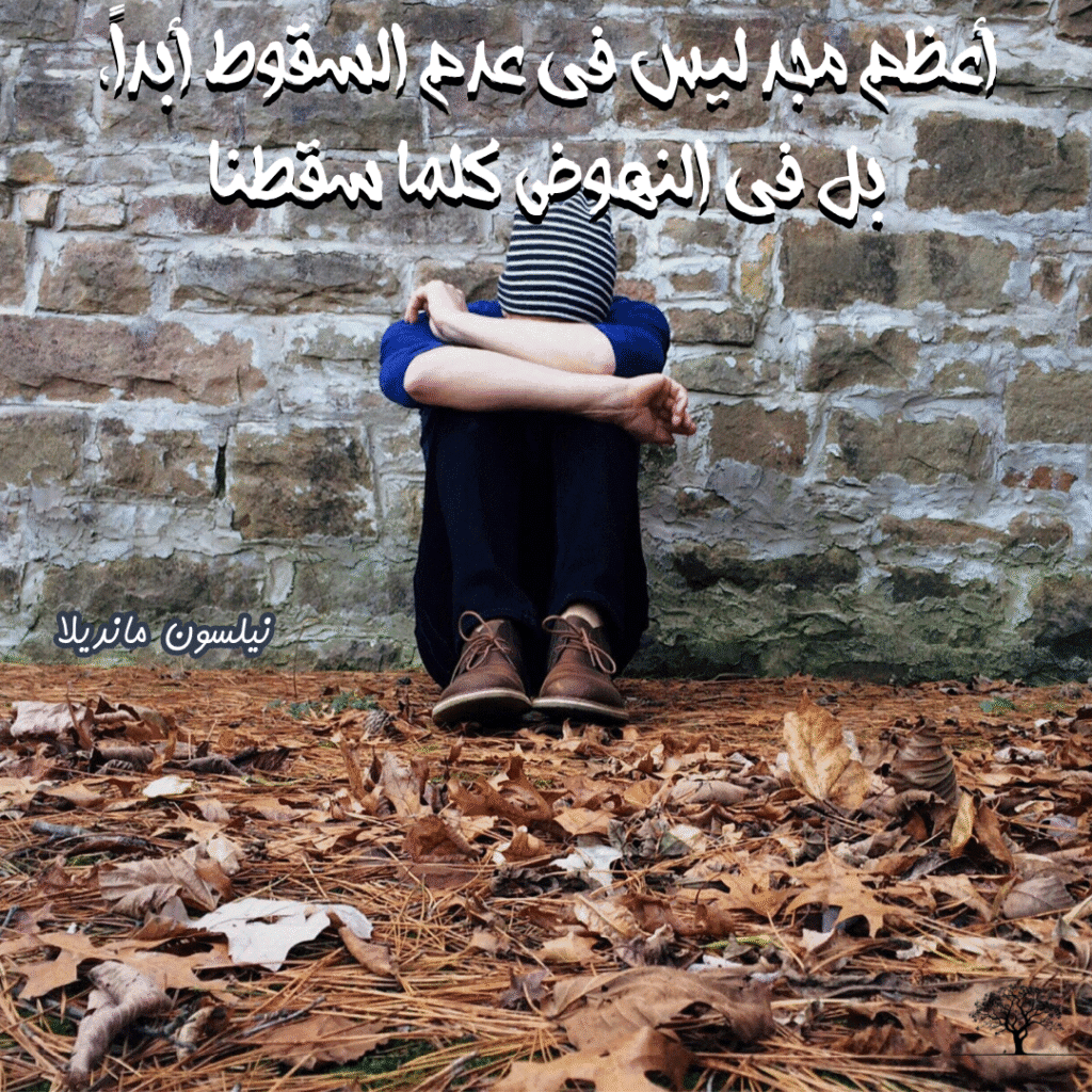 شخص جالس على الأرض وذراعيه حول ركبتيه أمام جدار حجري، محاط بأوراق شجر جافة، مع اقتباس لنيلسون مانديلا فوق الصورة: “أعظم مجد ليس في عدم السقوط أبداً، بل في النهوض كلما سقطنا.”