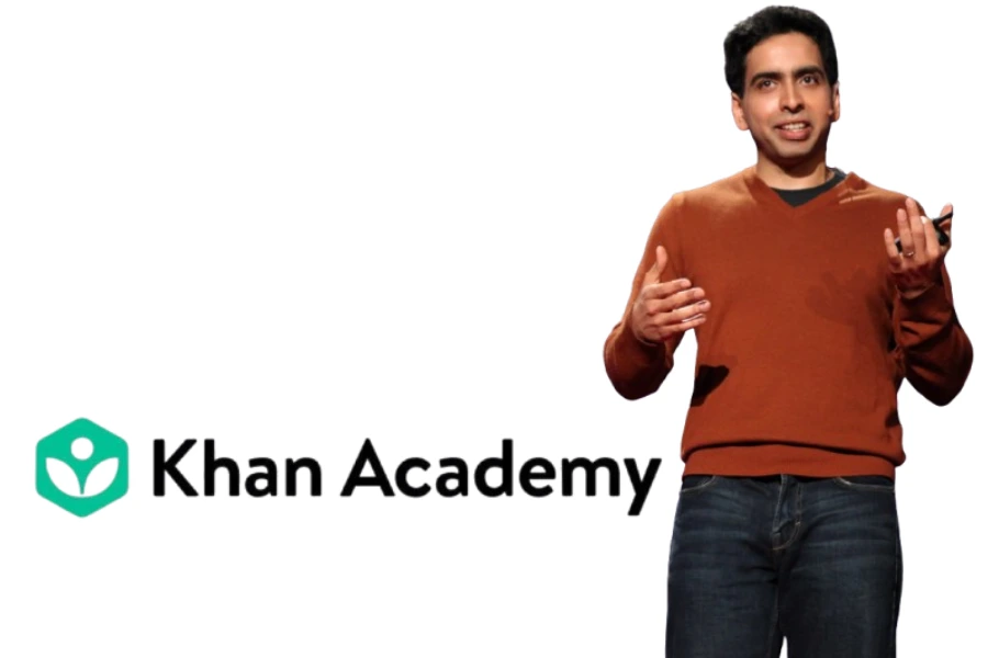 سلمان خان واقف أثناء إلقاء محاضرة، إلى جانبه شعار “Khan Academy” على خلفية بيضاء، يرمز للتعليم الرقمي المجاني.