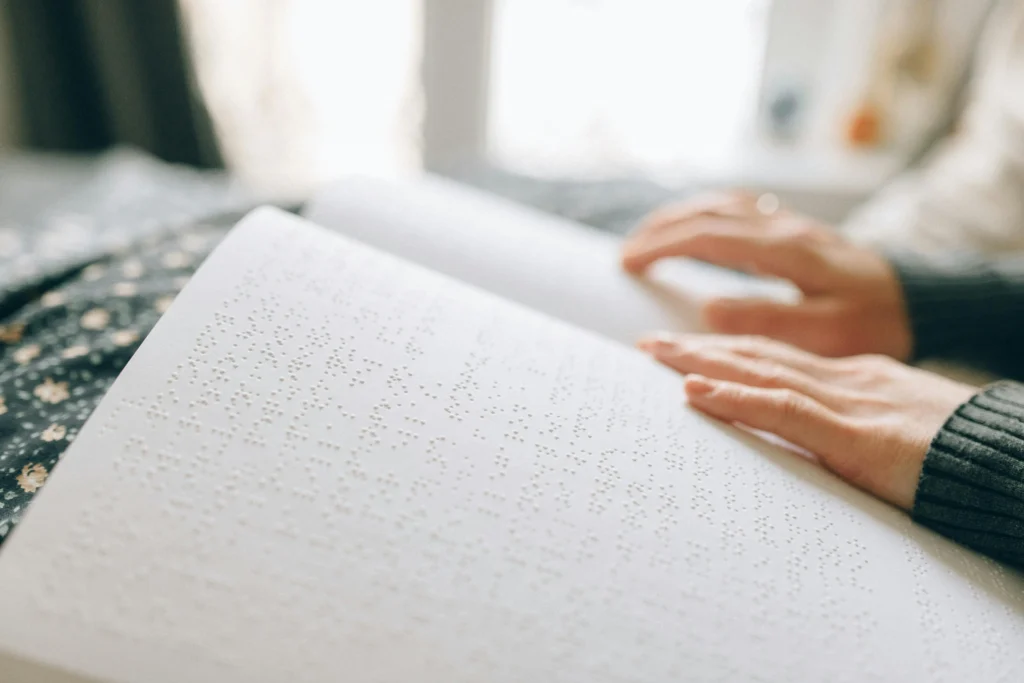 يدان تقرآن كتابًا بطريقة برايل، تجسيدٌ لتحدي الإعاقة البصرية