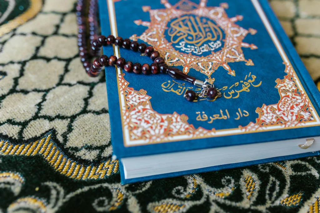 مصحف مزين بخرز وسجادة صلاة، يعبر عن قدسية القرآن الكريم وجماليات التعبد الإسلامي.