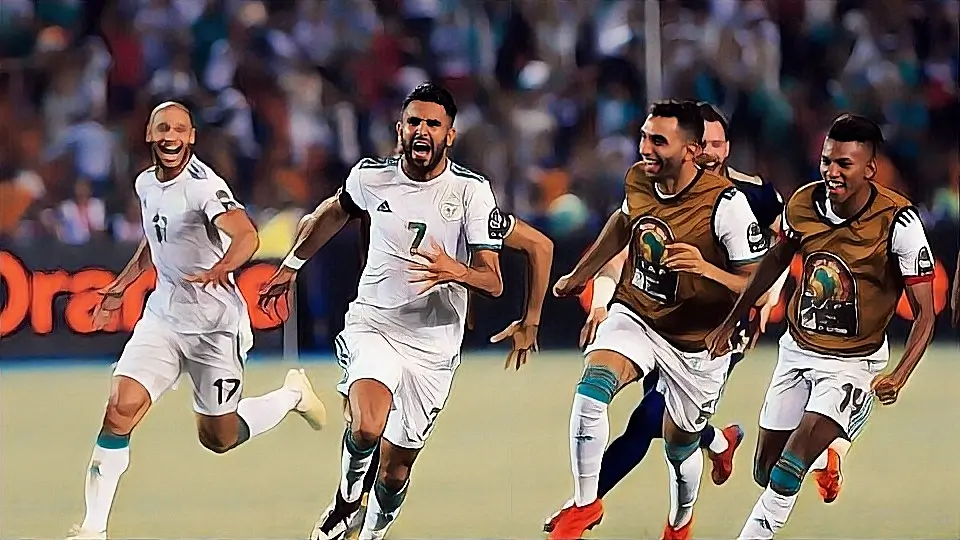 اللاعب الجزائري رياض محرز يحتفل بعد تسجيل هدف، مرتديًا قميص المنتخب الوطني.