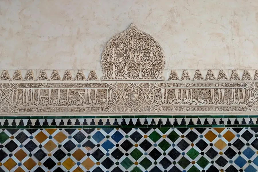 نقوش عربية هندسية على جدران قصر الحمراء في غرناطة، تمثل الإرث الثقافي والفني للغة العربية وتأثيرها التاريخي