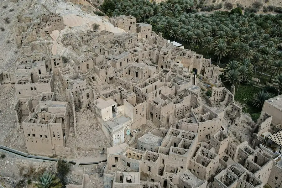 منظر جوي لقرية تاريخية مهجورة وسط الطبيعة، يظهر أنماطاً معمارية طينية منسيّة تعكس تأثير البيئة الجغرافية على الهوية الثقافية.