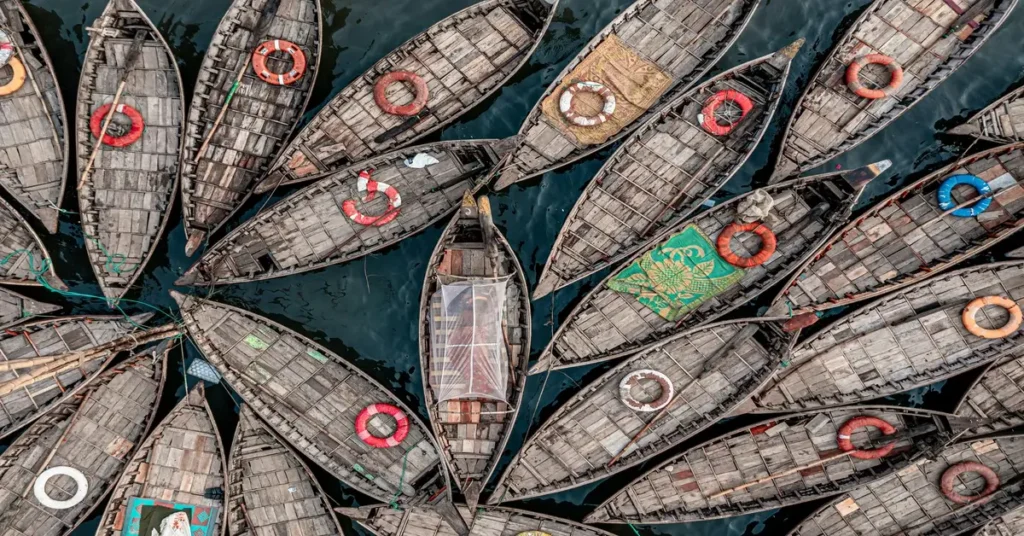 صورة جوية لقوارب خشبية تقليدية في نهر بنغلاديش تعكس تراث وثقافة السكان المحليين.