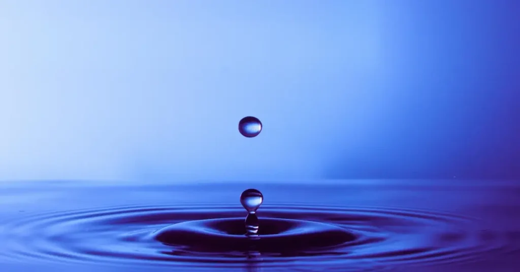 قطرات ماء تحدث تموجات على سطح سائل في مشهد يعكس قوانين الجاذبية.